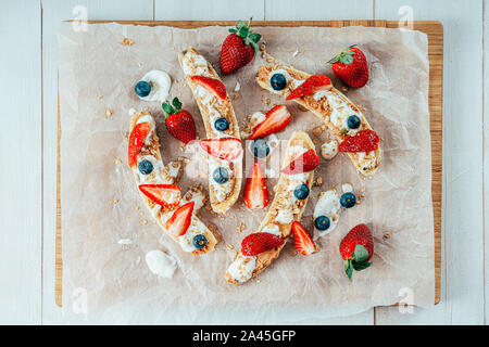 Banana Split mit Erdbeeren, Blaubeeren, Almond Butter und Honig Stockfoto