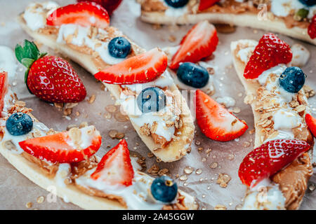 Banana Split mit Erdbeeren, Blaubeeren, Almond Butter und Honig Stockfoto