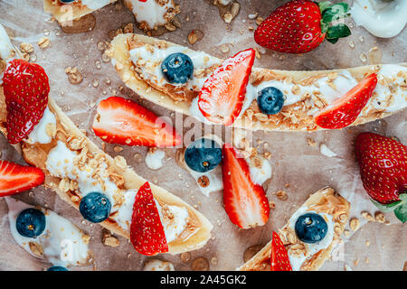 Banana Split mit Erdbeeren, Blaubeeren, Almond Butter und Honig Stockfoto