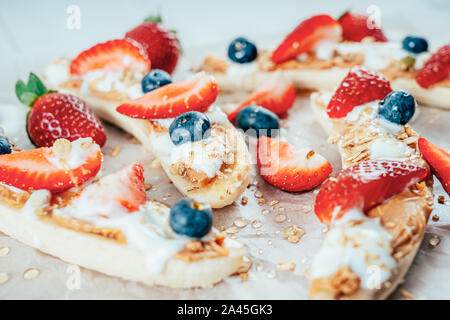 Banana Split mit Erdbeeren, Blaubeeren, Almond Butter und Honig Stockfoto