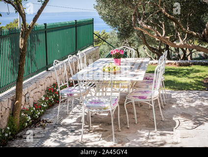 Wunderschöner Garten, Tisch für eine Mahlzeit und Blick auf das Mittelmeer vorbereitet Stockfoto