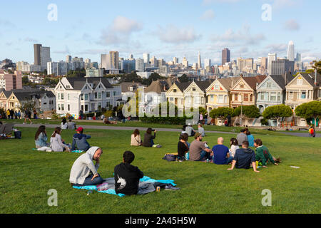 SAN FRANCISCO, VEREINIGTE STAATEN - 8 September, 2019: die Menschen entspannen in Alamo Square Park an einem warmen Tag mit Blick auf den berühmten Painted Ladies und die Skyline der Stadt Stockfoto