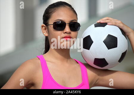 Unemotional Filipina Person mit Fußball Stockfoto