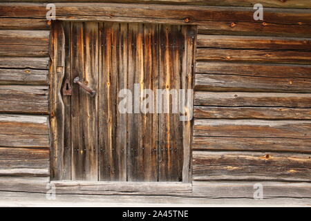 Alt und rustikal Luke auf einem Baumstamm Hütte. Stockfoto