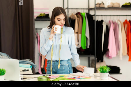 Frau auf der Suche nach Maß durch Skizzen arbeiten In Kleidung Atelier Stockfoto