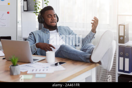 Freundliche Mitarbeiter virtuelle Gitarre spielen und Musik hören am Arbeitsplatz Stockfoto