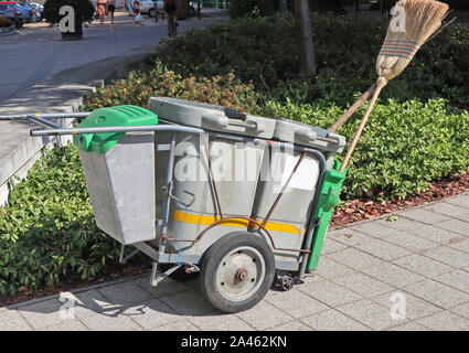 Mülltonne mit Rädern mit Besen auf der Straße Stockfoto