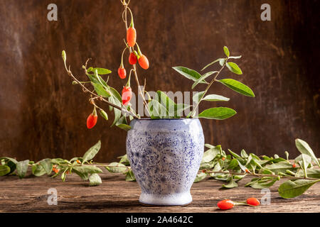 Frische Goji Beeren mit Blätter auf einen hölzernen Tisch Stockfoto