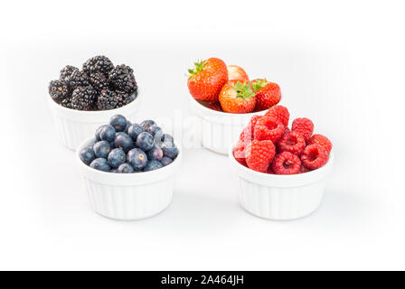 Blaubeeren, Himbeeren, Erdbeeren und Brombeeren in förmchen vor weißem Hintergrund Stockfoto