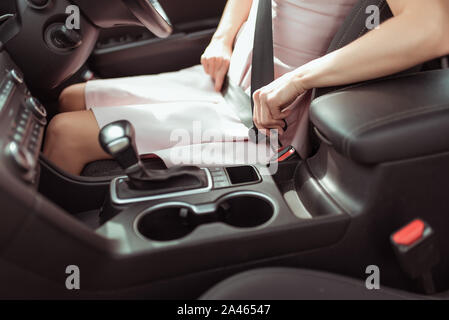 Frau Befestigung Sicherheitsgurt im Auto, bei Rechts- und Linksverkehr im Fahrgastraum. Automatikgetriebe. Verkehrssicherheit Konzept Stockfoto