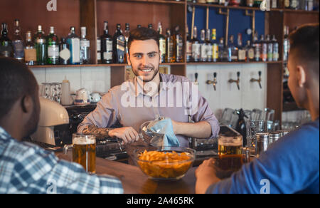 Attraktive junge Barkeeper polieren Gläser, im Gespräch mit den Kunden Stockfoto