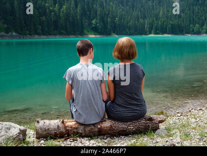 Menschen, Mutter mit Sohn, Rest auf Baum am Schwarzen See anmelden, Crno jezero, Ufer, Sommer Landschaft. Zabljak Gemeinde, Montenegro. Stockfoto