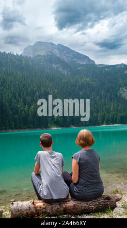 Menschen, Mutter mit Sohn, Rest auf Baum am Schwarzen See anmelden, Crno jezero, Ufer, Sommer Landschaft. Zabljak Gemeinde, Montenegro. Stockfoto