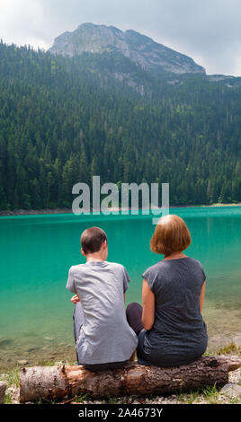 Menschen, Mutter mit Sohn, Rest auf Baum am Schwarzen See anmelden, Crno jezero, Ufer, Sommer Landschaft. Zabljak Gemeinde, Montenegro. Stockfoto