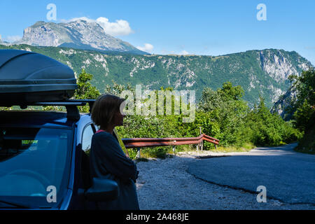 Die Frau in der Nähe von Auto (unkenntlich) auf sekundären Landschaft Straße durch Mountain Nationalpark Durmitor, Montenegro, Europa. Fokus auf Hintergrund (foregr Stockfoto