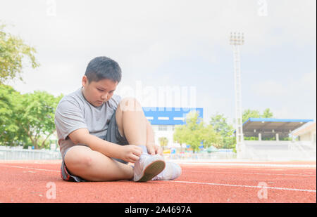 Übergewichtige junge Schnürsenkel binden vorbereiten zu lassen. Fat Boy Jogger immer zum joggen am Anschluss bereit. Übung, um Gewicht zu verlieren Stockfoto