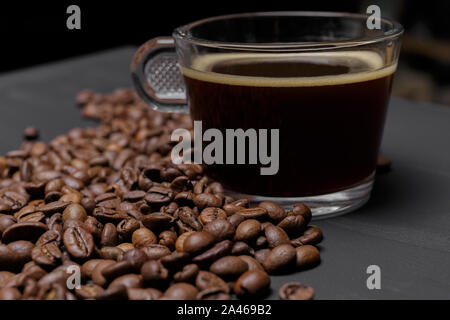 Kaffeebohnen und Tasse Kaffee auf schwarz lackierten Hintergrund Stockfoto
