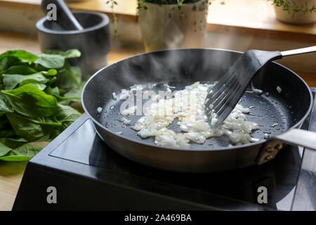 Die Zwiebeln werden mit viel Dampf in einem schwarzen Pan, Kochen und Küche Konzept, ausgewählte Schwerpunkte fried Stockfoto