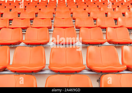 Reihen von leeren orange Kunststoff Tribünenplätze bei einem Indoor Sport Stadion. Nahtlose Muster von Stadion / ARENA Stühle auf der Haupttribüne für Sport Konzept bac Stockfoto