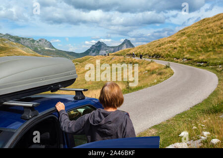 Frau mit Auto (Modell unkenntlich) auf Durmitor Panoramastraße. Malerische Sommer Bergwelt des Nationalpark Durmitor, Montenegro, Balkan Stockfoto