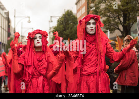Marble Arch, London, Großbritannien. Oktober 2019. Umweltbegräbnisprozession, Stärke in Trauer, organisiert von Extinction Rebellion. Eine Gruppe von Performance-Aktivisten in rotem Gewand nimmt an einer symbolischen öffentlichen Demonstration auf einer britischen Stadtstraße Teil. Ihre theatralischen Kostüme, weiße Gesichtsfarbe und expressiven Gesten erinnern an Themen wie Umweltdringlichkeit, soziale Gerechtigkeit und künstlerischen Protest. Zuschauer und urbane Architektur prägen die Szene. Penelope Barritt/Alamy Live News Stockfoto