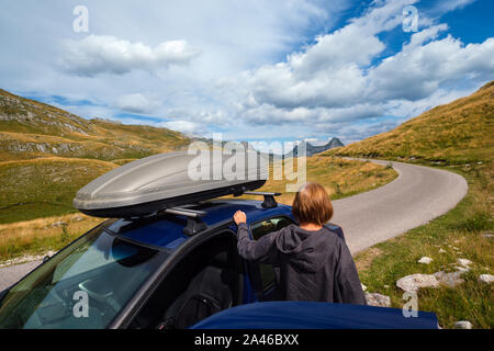 Frau mit Auto (Modell unkenntlich) auf Durmitor Panoramastraße. Malerische Sommer Bergwelt des Nationalpark Durmitor, Montenegro, Balkan Stockfoto