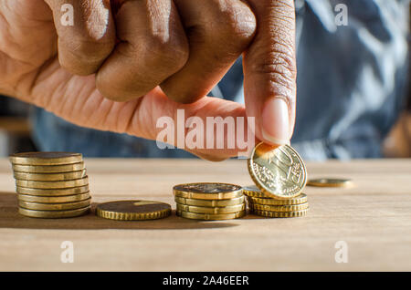 Nahaufnahme einer schwarzen Frau Hand zählen Euro Münzen auf einen hölzernen Tisch. Selektiver Fokus, Stockfoto