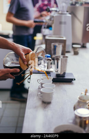 Man gießt kalten Kaffee brühen in Glas auf dem Tisch Stockfoto
