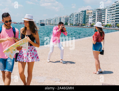 Ein paar ist das Lesen einer Karte, während die anderen Fotos ist, die ihren Sommer Urlaub. Stockfoto