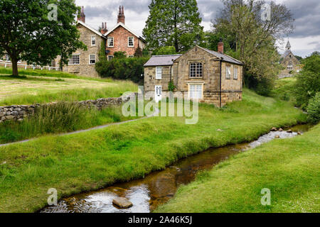 Hutton Beck fließt durch Hutton-le-Hole Dorf mit Häusern aus Stein auf dem Village Green North York Moors National Park England Stockfoto