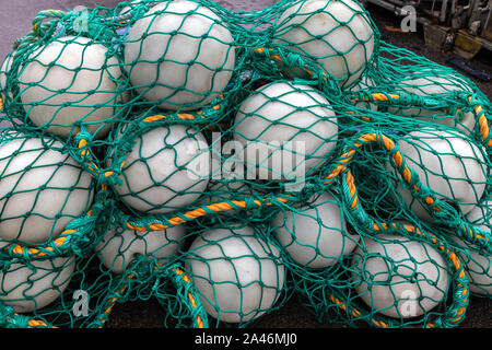 Stapel der Fischerei Bojen und grünen Fischernetze, auf einem Kai im Hafen von Bergen, Norwegen Stockfoto