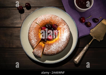 Runde Kirschtorte in der Platte auf hölzernen Tisch. Dunkle Essen Stockfoto