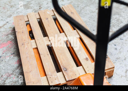 Orange Hubwagen, Gabelhubwagen mit leere Palette, Hubwagen Transport Lagerung Stockfoto