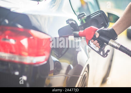 Pumping Gas an der Pumpe. Nahaufnahme der Mann pumpen Benzin im Auto an der Tankstelle Racing Handschuhe tragen. Verblasste Wirkung. Stockfoto