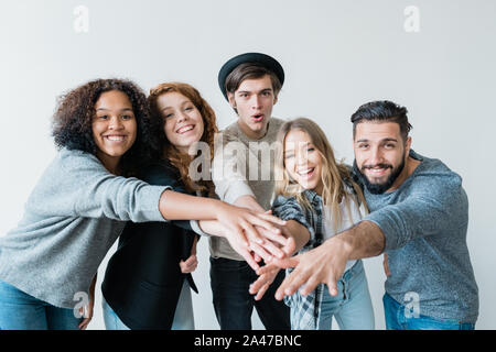 Junge verspielte interkulturelle Freunde in casualwear Betrachten Sie mit Lächeln Stockfoto