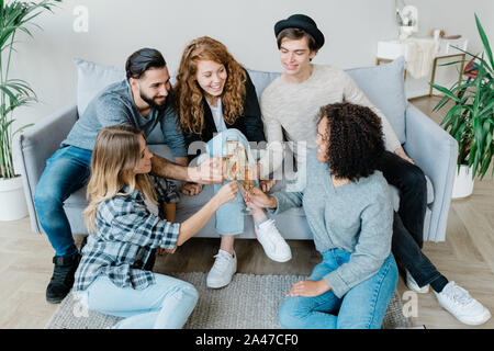 Fünf junge fröhliche Freunde in casualwear Klirren mit Flöten Champagner Stockfoto