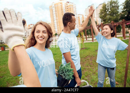 Freiwilligenarbeit. Die jugendlichen Freiwilligen im Freien Anpflanzen von Bäumen eine hohe fünf erfolgreiche close-up Stockfoto