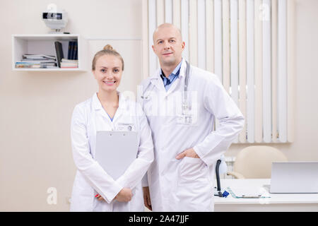 Zwei erfolgreiche zeitgenössische Kliniker in whitecoats durch ständigen Arbeitsplatz Stockfoto