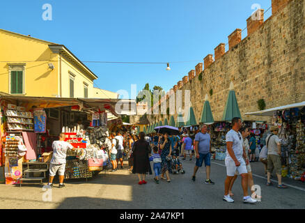 Blick auf die Straße des berühmten Reiseziel mit Menschen kaufen bei Souvenirstände und die alten Mauern der Stadt an einem sonnigen Sommertag, Pisa, Toskana, Italien Stockfoto