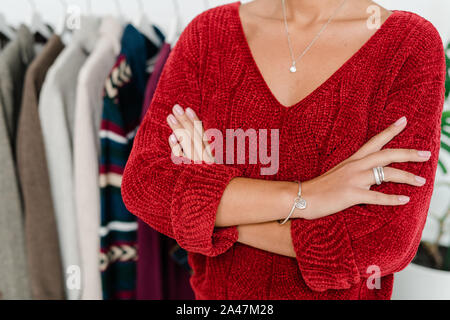 Junge elegante Frau in Rot Strickpullover überqueren, um die Arme Brust Stockfoto