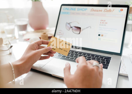 Zeitgenössischen weiblichen Shopper holding Bank Card über Laptop Tastatur Stockfoto