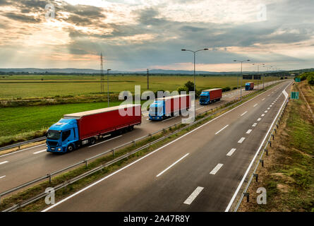 Lkw Lkw in einen Wohnwagen oder ein Konvoi auf Land Autobahn unter einem schönen Himmel Stockfoto