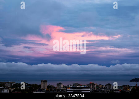 Lebendige Himmel von rosa und blau Farben beim Sonnenuntergang. Schöne Skyscape mit Wolken bei Sonnenuntergang über einer Stadt am Meer. Abend Landschaft. Stockfoto