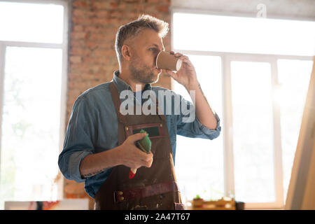 Mitte - gealterte Maler in Arbeitskleidung trinken heißen Kaffee bei Bruch von Arbeitsplatz Stockfoto
