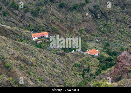 Nordöstlich von La Gomera. Landhaus von Palmen und Sonnenkollektoren im Garten umgeben. Alte vulkanische Berge von grünen Gras bedeckt, Lorbeeren ein Stockfoto