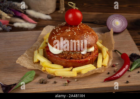 Cheeseburger aus gehacktem Rindfleisch Schnitzel mit Tomaten. Holz- Hintergrund. Close-up. Stockfoto