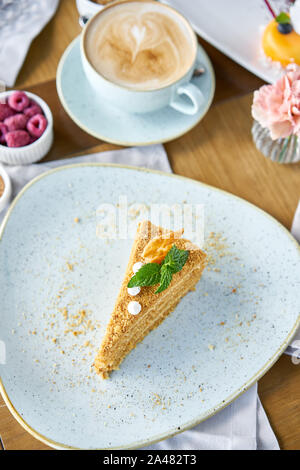 Honig Kuchen mit Baiser und Minze dekoriert.. Frühstück im Café, Kaffee am Morgen. Cappuccino und viele Desserts auf dem Tisch. Stockfoto