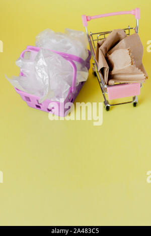 Polyäthylen und Säcke aus Papier in einem Warenkorb auf gelbem Hintergrund. Stockfoto