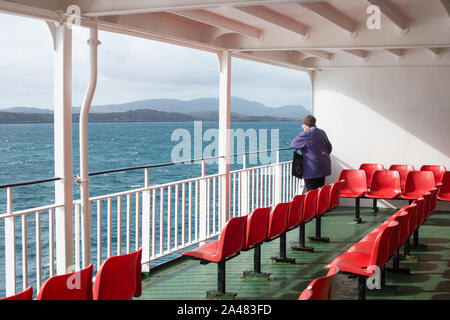 Ein einsamer Reisender auf dem Deck eines Autofähre Segeln auf den Äußeren Hebriden in Schottland. Großbritannien Stockfoto