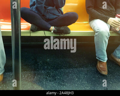 Junge Frau, die mehr als einen Sitz in der New York City U-Bahn (U-Bahn), NYC, USA, belegt Stockfoto